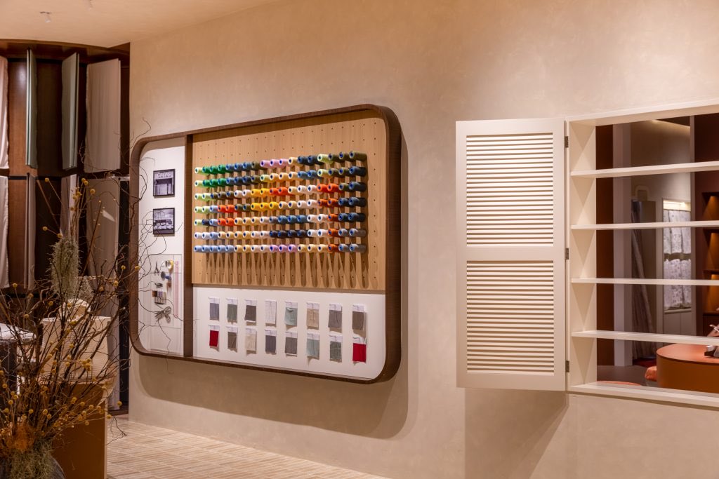 A framed board of thread spools and swatch cards