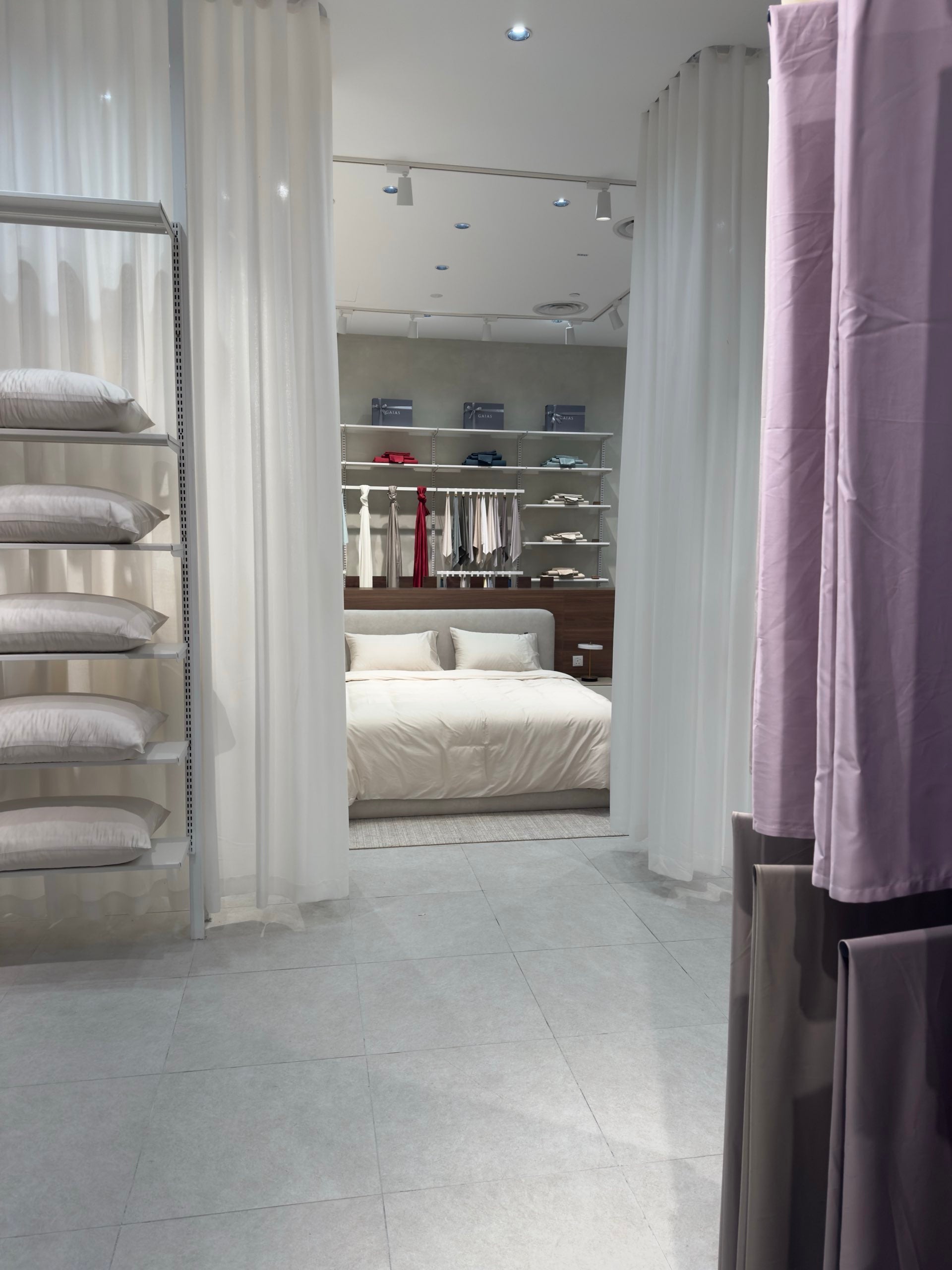 Sheer curtains dividing rooms, with a dressed bed beyond