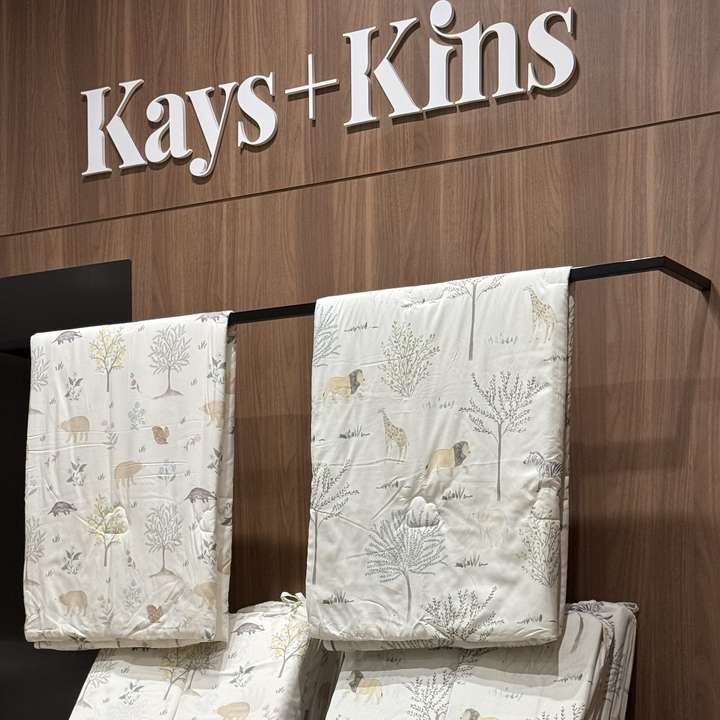 The Kays+Kins sign above quilts on a walnut wall
