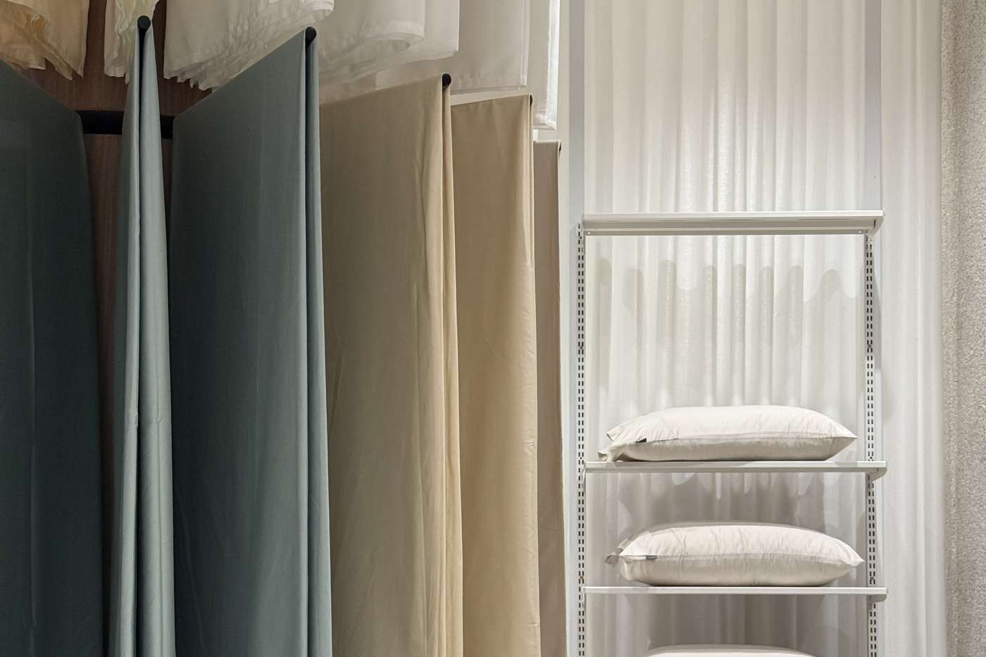 Fabric hanging full length beside shelves of stacked pillows