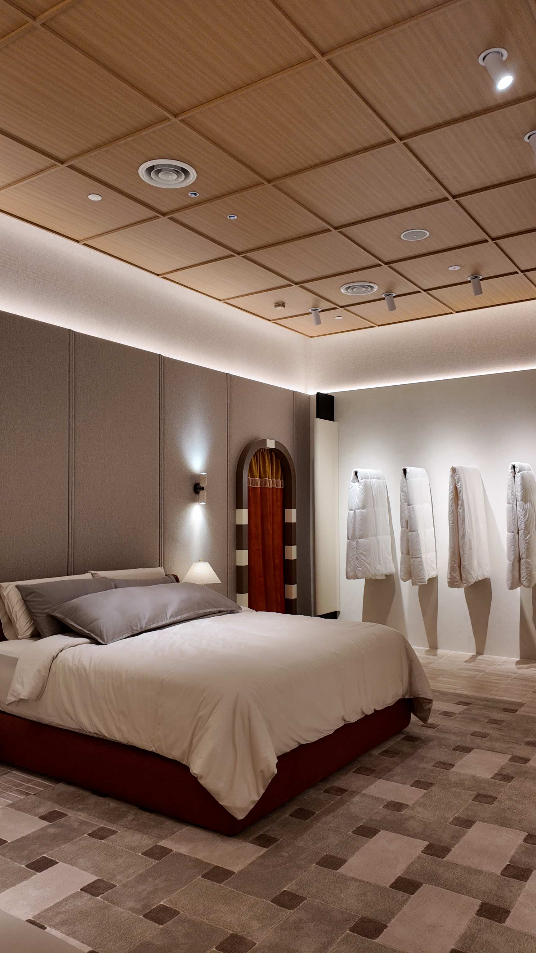 A dressed bed under a coffered timber ceiling